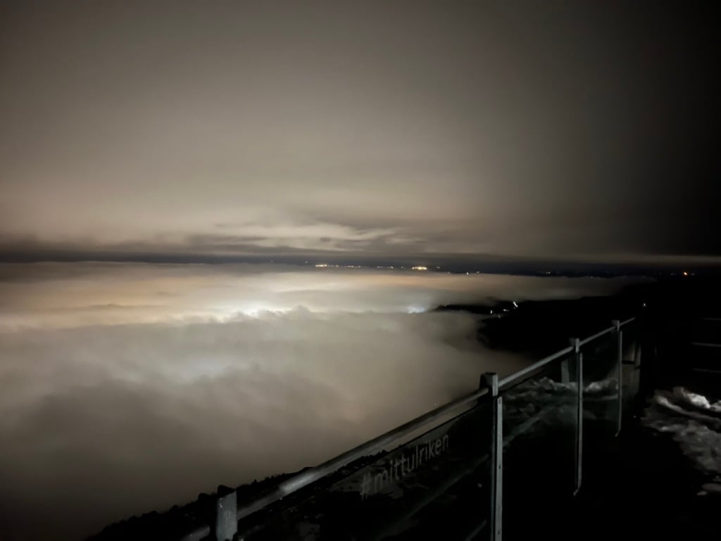 Utsikt fra Ulriken på kvelden; byen Bergen er innhyllet i tåke og lyser trolsk